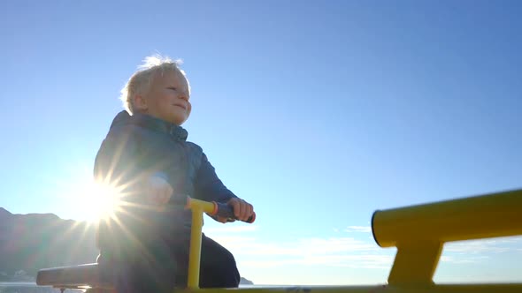 Three Year Old Boy Swinging on a Swing in the Sunny Morning on the Beach