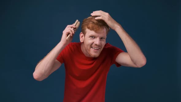 a Handsome Confident Man Combing His Hair on a Blue Background