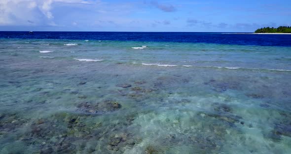 Wide flying abstract shot of a paradise sunny white sand beach and aqua blue ocean background 