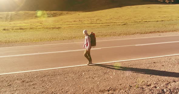 Flight Over Hitchhiker Tourist Walking on Asphalt Road