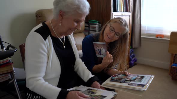 Closeup of two women looking at photo memories out of a photo album.