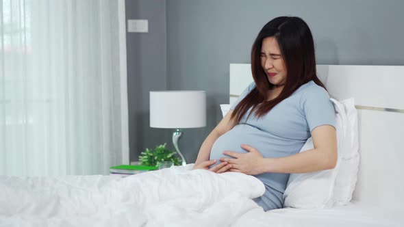 pregnant woman has a stomachache on a bed