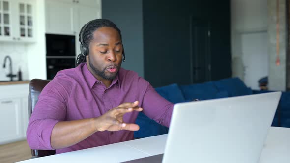 Happy AfricanAmerican Man with Locks Hair Wearing Wireless Headset Sitting at Home