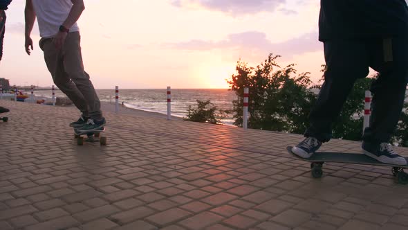 Group of Young People Skateboarding on the Road in the Early Morning Near the Sea Close Up Shot