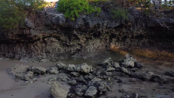 Fly Over Small Rock Cliff in Low Tide in Sunset