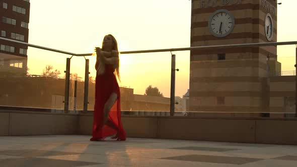 Beautiful Young Girl Dancing on the Street of a Modern City in the Sunset Light