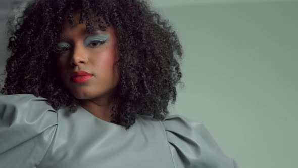 Mixed Race Woman with Big Curly Hair in Leather Fashion Dress in Studio