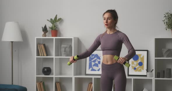 Sporty Adult Woman Is Training with Dumbbells in Apartment Caring About Health and Good Physical