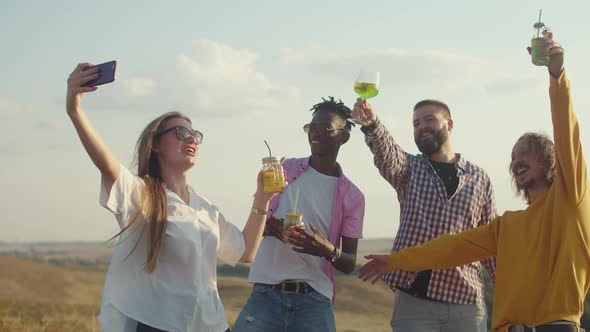 Man Drinks Cocktail Through a Straw and Talks to Woman in Nature Against the Background the Sun