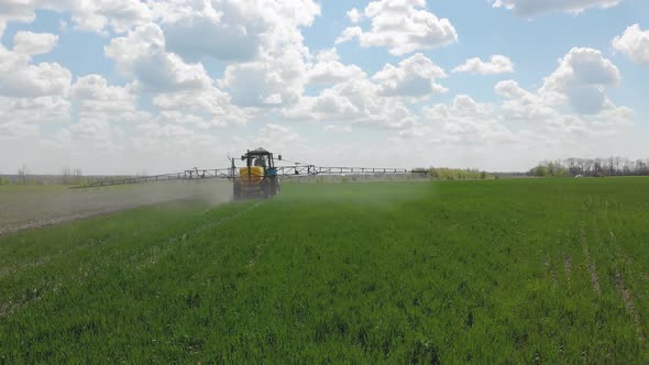 Aerial View of Farming Tractor Spraying on Field with Sprayer, Herbicides and Pesticides at Sunset