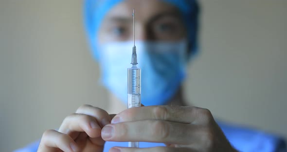 Doctor Holds the Syringe in His Hands