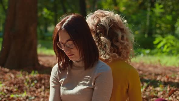 Two Happy Young Women are Having a Great Time in the City Park One Girl is Playing the Guitar the