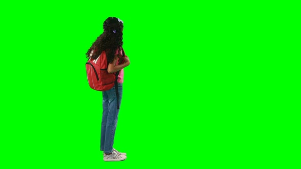 Girl with schoolbag standing against green background 4k
