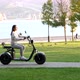 Young girl on electric scooter is riding through public park at sunny morning - VideoHive Item for Sale