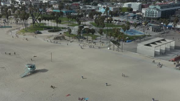 AERIAL: Flight Towards Venice Beach Skatepark and Boardwalk with Palm Trees and Bike Lane, Sunny