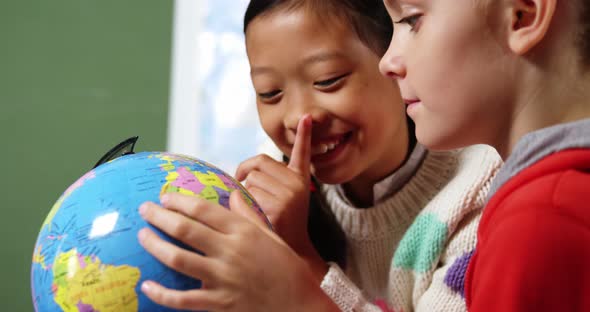 School kids looking at globe in classroom at school