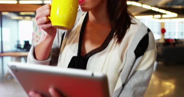 Businesswoman using digital tablet while having coffee