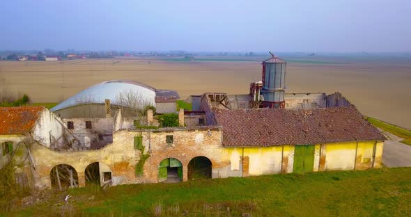 Birds Fly Near Abandoned Farmhouse with Old Water Tower