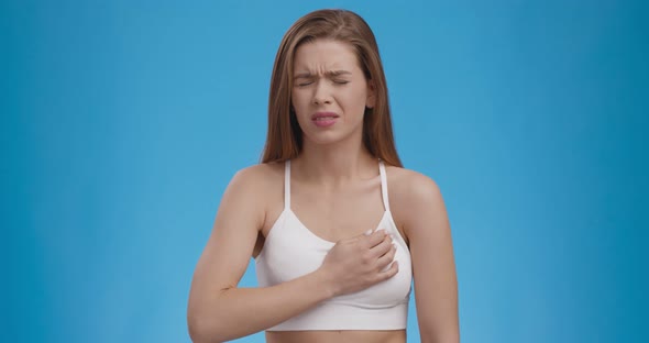 Heart Attack Threat. Caucasian Woman Feeling Strong Pain in Chest, Blue Background