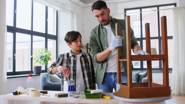 Father and Son Stirring Grey Color Paint at Home