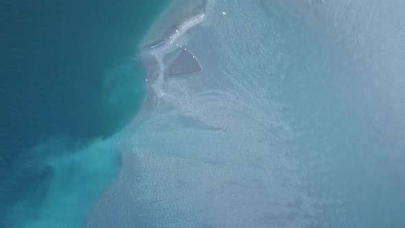 Top view of waterfront of idyllic blue lake with different colors and a flock of birds crossing the