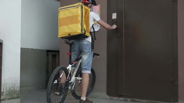 Food delivery service during the quarantine period on a bicycle in a yellow thermo backpack.