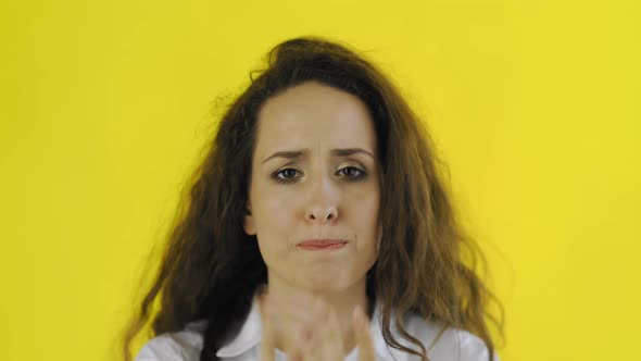 Sad Thoughtful Young Beautiful Woman in Shirt Standing in Studio with Yellow Background