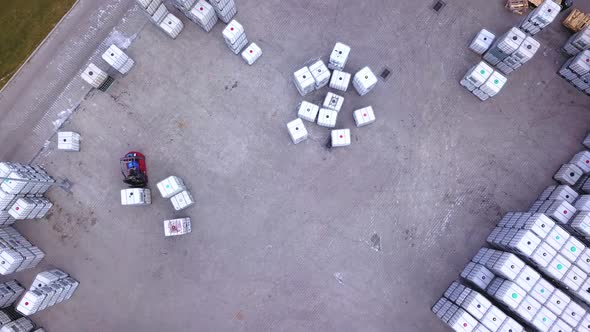 Forklift truckse between large shelves at outside warehouse and load pallets.Aerial. Drone shot