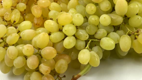 Large bunch of ripe white grapes lies on a white table, background