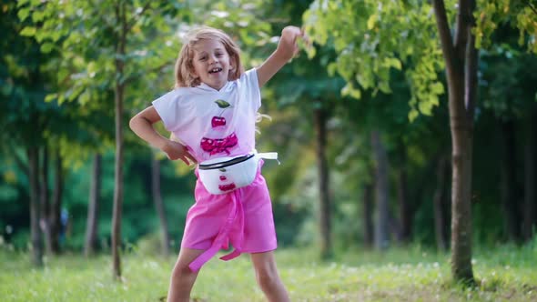 Positive little girl dancing happily in the park