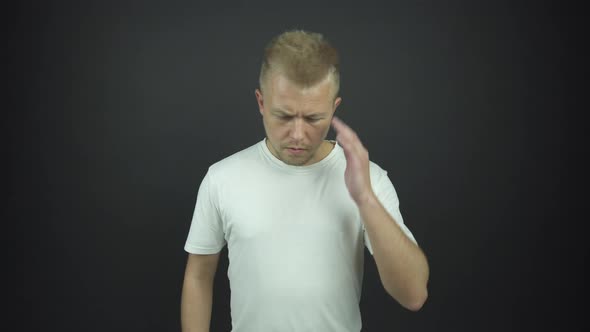 Disappointed Guy with Fair Hair Holds Hand on Forehead