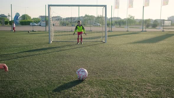 Young Boy Goalie in Football Uniform Misses Shot