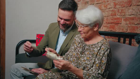 European Pensioner Mother Laughs Out Loud While Looking at Old Photographs and Celebrating Mother's