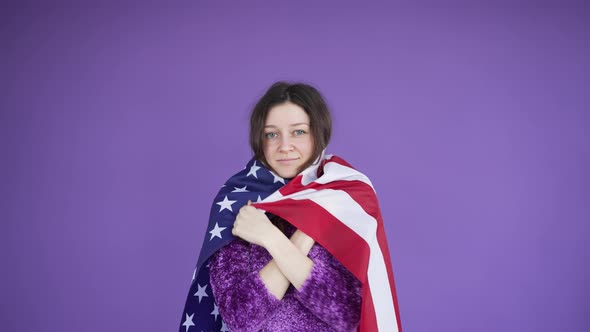 Portrait of a Beautiful Darkhaired Woman Wraps Herself in an American Flag and Looks at the Camera