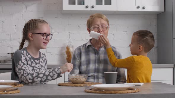 Grandchildren Helping Grandmother During Breakfast