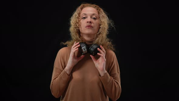 Front View of Serious Woman Taking Off Headphones and Talking Looking at Camera