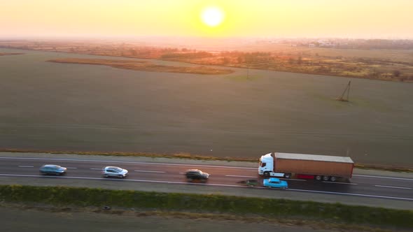 Aerial View of Semitruck with Cargo Trailer Driving on Highway Hauling Goods in Evening