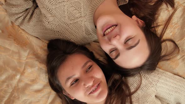 Camera Rotating Over Two Teenage Girls Lying on Bed and Talking