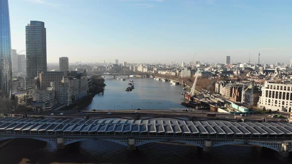 Reverse aerial view of Blackfriars train station over river Thames on a hazy sunny day