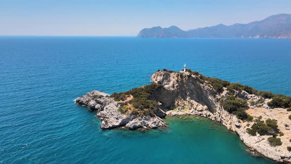 drone flight over the island on which there is a lighthouse inside the mediterranean sea against the