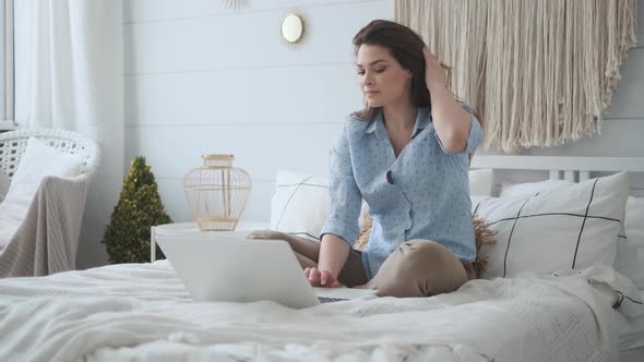 Young Girl Working on a Laptop While Sitting on the Bed