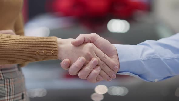 Closeup Handshake of Dealer and Client in Car Showroom