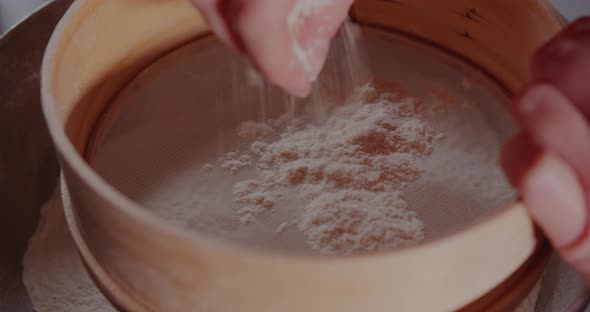 Woman Sifts Flour Through Sieve in the Kitchen While Baking Croissants