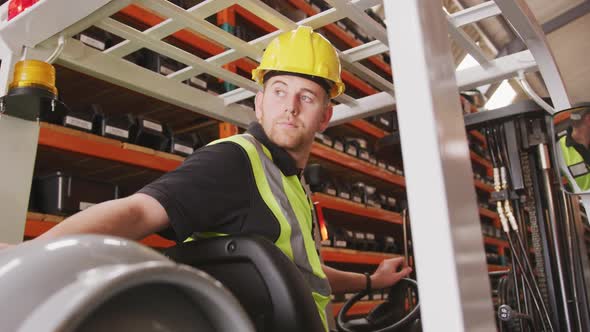 Caucasian male factory worker at a factory with a hat and high vis vest, using a truck