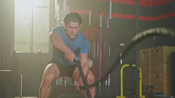 Caucasian young handsome active male athlete or sportsman practicing exercise by using battle Rope.