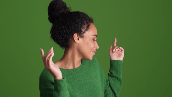 Positive African woman in green shirt dancing