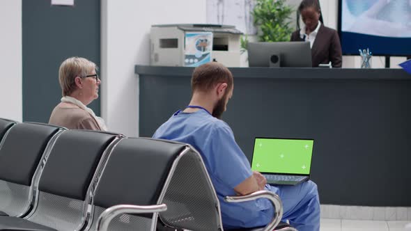 Male Nurse Analzying Greenscreen Display on Laptop in Waiting Room