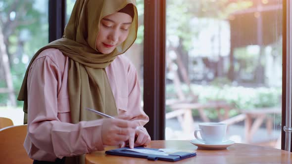 Young beautiful Asian Muslim women enjoying a relaxing moment working and playing with mobile phone