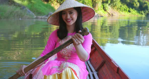 Vietnamese Woman Rowing A Boat And Looking At Camera