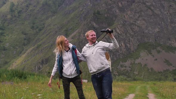 Couple in Love Travels in the Mountains with a Map and Binoculars. Friends Travelers Are Looking for